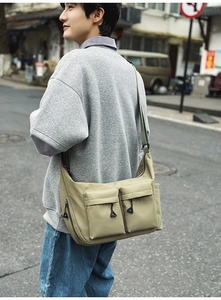 Detail view of khaki nylon messenger bag with multiple zipper pockets and adjustable strap