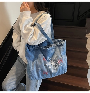 Detailansicht der Denim-Tasche mit weißem Spinnennetz und roter Spinnenstickerei