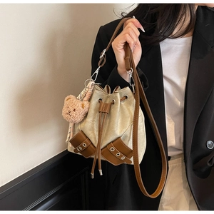Detail der zweifarbigen Tunnelzug-Beuteltasche mit süßem Plüschbär-Anhänger am schwarzen Blazer