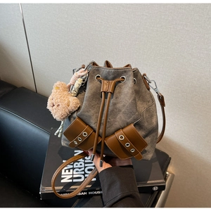Detail der Canvas-Beuteltasche mit Lederbesatz und dekorativem Plüschbär-Anhänger