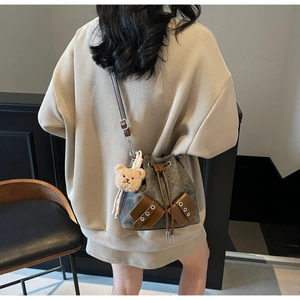 Detail der grauen Vintage-Canvas-Beuteltasche mit braunen Ledertaschen und Bärenanhänger