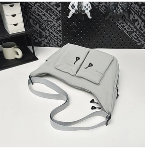 Close-up of light grey water-resistant nylon bag with utility pockets and wide strap