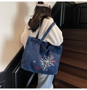 Detail der blauen Denim-Tragetasche mit Spinnennetz-Stickerei als Schultertasche