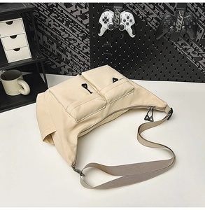 Detail of water-resistant nylon shoulder bag featuring front utility pockets and sturdy strap