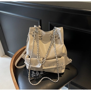 Detailed view of beige faux leather bucket bag with silver chain straps and rivet pockets