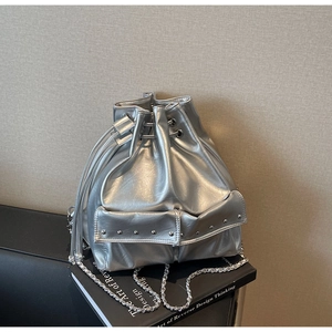 Detail of silver metallic bucket bag with drawstring closure and rivet pockets on a book