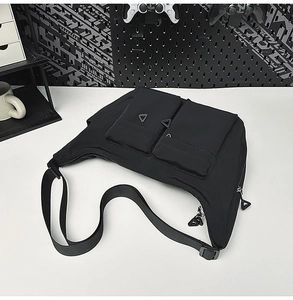Close-up of black nylon crossbody bag with double front utility pockets and zippers