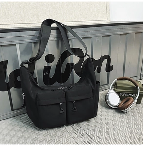 Detail of black nylon tactical crossbody bag with dual zippered pockets and utility design