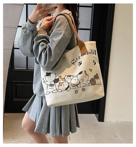 Detail of off-white canvas tote with brown straps and cartoon cat print for daily use