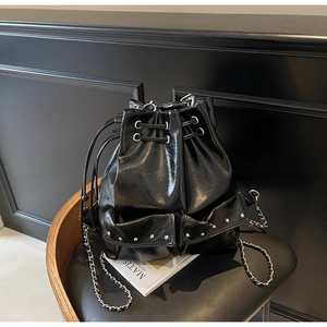 Detail of black patent leather bucket bag featuring silver rivets and chain strap