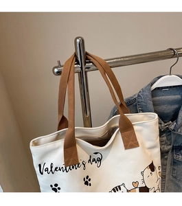 Detail of white canvas tote bag with Valentine's day cat print and brown strap