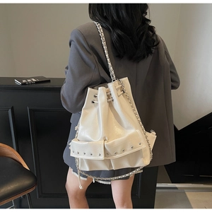 Model wearing a white PU leather bucket backpack with drawstring and silver rivets