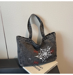 Detail der grauen Vintage-Jeans-Tasche mit aufwendiger Spinnen- und Netzstickerei
