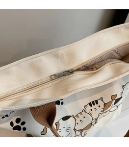 Detail of canvas tote bag showing zipper closure, inner lining, and cat print