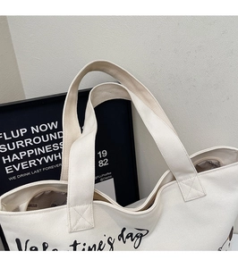 Detail of canvas tote bag showing zipper closure and Valentine's Day script print
