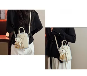 Detail of a chic beige mini handbag featuring blue piping and a cute plush bear charm