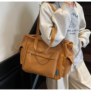 Detail of a ginger yellow large nylon tote bag with side drawstring and front zipper