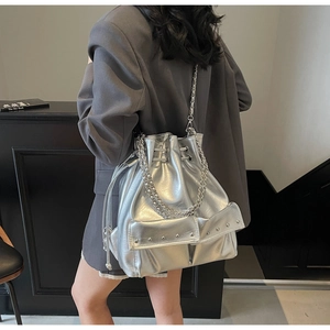 Detail view of silver metallic bucket bag with chain straps and drawstring closure