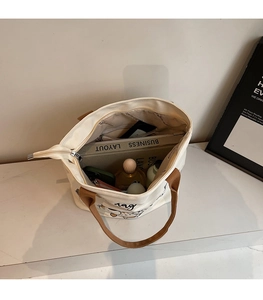 Top-down view of a spacious canvas tote bag showing organized interior pockets and daily items