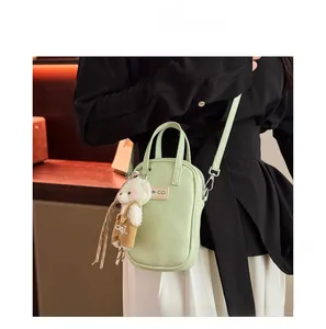 Detail of light green litchi textured phone bag with a cute plush bear charm accessory