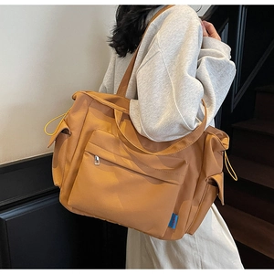 Detail of a large mustard nylon tote bag with functional zippers and adjustable drawstrings