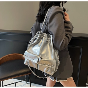 Detail of silver metallic bucket bag with studded pocket and delicate chain strap