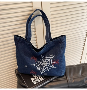 Detailaufnahmen der Stickereien mit weißen Spinnennetzen auf blauem Denim-Shopper