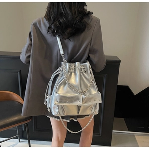 Detail of silver metallic bucket bag featuring chunky chain strap and rivet embellishments