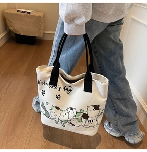 Detail of large canvas tote bag with black straps and cute cartoon cat prints