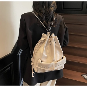 Detail of beige faux leather bucket backpack with silver rivets and chain straps