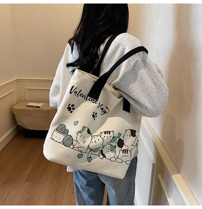 Detailed side view of canvas tote bag with cartoon cat print on female shoulder