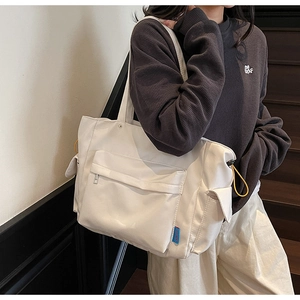 Detail of canvas tote bag featuring large front zipper pocket and yellow drawstring