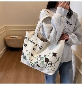 Close-up of off-white canvas tote bag featuring cute cartoon cat prints and hearts