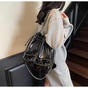 Detail of black leather bucket bag with silver chain straps and punk rivet accents