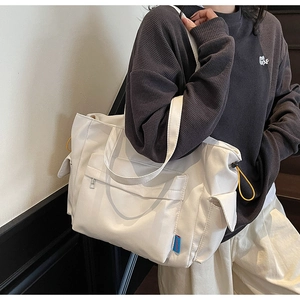 Detail of white canvas tote bag featuring functional side pockets and yellow drawstrings