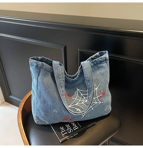 Detailansicht der Spinnennetz-Stickerei auf der dunkelblauen Denim-Tragetasche
