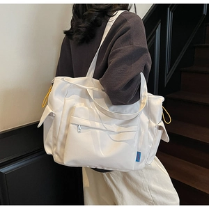 Detail of white large capacity tote bag featuring multi-pocket design and yellow drawstrings