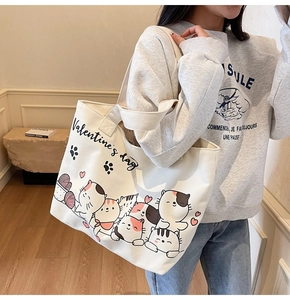 Detail of white canvas tote bag featuring cute cartoon cat prints and Valentine text