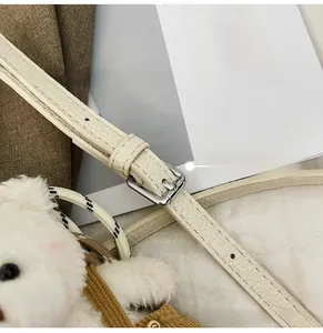 Detail of white litchi pattern leather strap with silver buckle and plush bear charm
