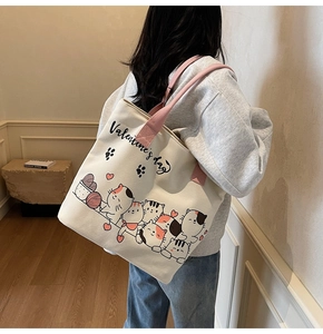 Back view of a woman wearing the large canvas tote bag with pink straps and cat graphics