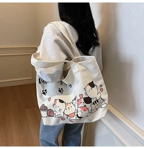 Close-up of cream canvas tote bag featuring cute cartoon cats and heart prints