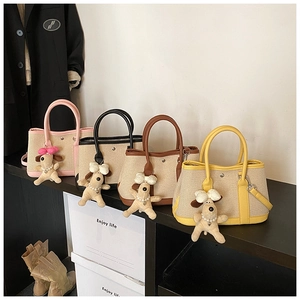 Detail of canvas tote bags with leather trim and plush puppy charms on a display