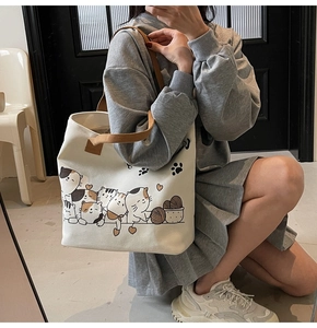 Detailed view of large canvas tote bag with cute cat illustrations and brown handles
