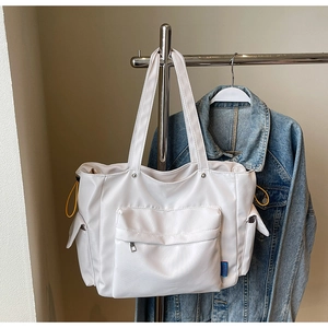 Close-up of white tote bag with large zipper pocket and bright yellow drawstring details