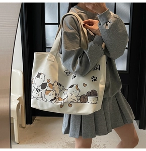 Close-up of cream canvas tote bag featuring cute cartoon cats and yarn balls
