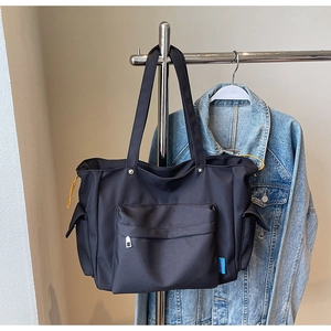 Detail of black nylon tote bag with yellow drawstring and functional zipper pocket