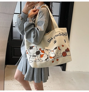 Detail of off-white canvas tote bag featuring cute cartoon cats and mirror selfie style