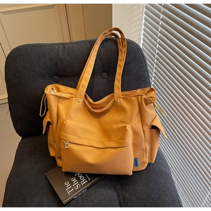 Close-up of ginger yellow canvas tote bag with side pockets on a dark velvet chair