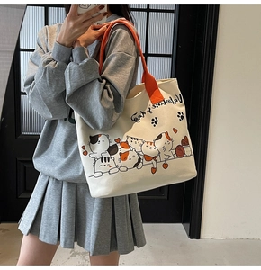 Detail of canvas tote bag with orange straps and colorful cartoon cat prints