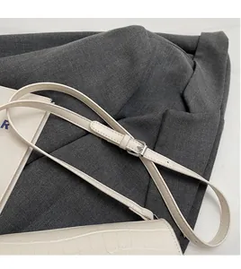 Detail view of white croc-embossed leather handbag with adjustable silver buckle strap